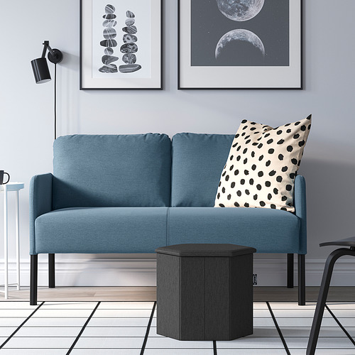 Sala de estar moderna: sofá azul con almohada de puntos, mesa auxiliar negra, arte de pared, pared gris.