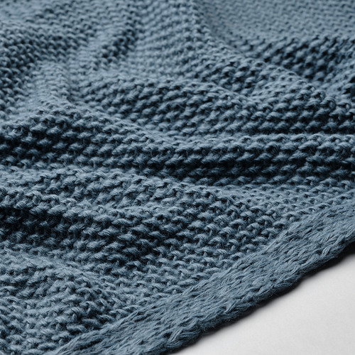 Primer plano de una suave manta de punto gris azulado, que muestra texturas intrincadas y artesanía de alta calidad.