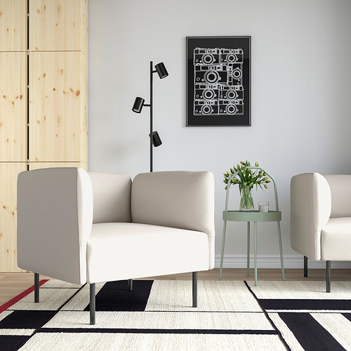 Moderno salón con sofá blanco LILLEHEM y mesas auxiliares. Decorado con una alfombra geométrica, una obra de arte y un taburete verde con flores.