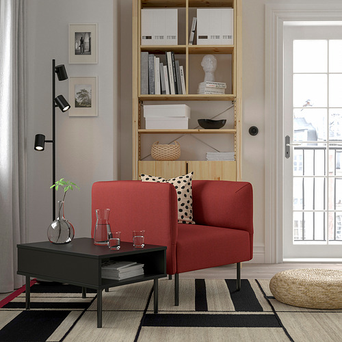 Sala de estar moderna con sofá rojo, estantería, mesa de café, alfombra, lámpara y luz natural.