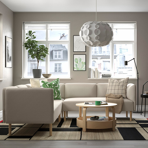 Moderno salón con sofá beige en forma de L lillem, mesa de centro de madera, gran ventanal, lámpara colgante, planta y alfombra.