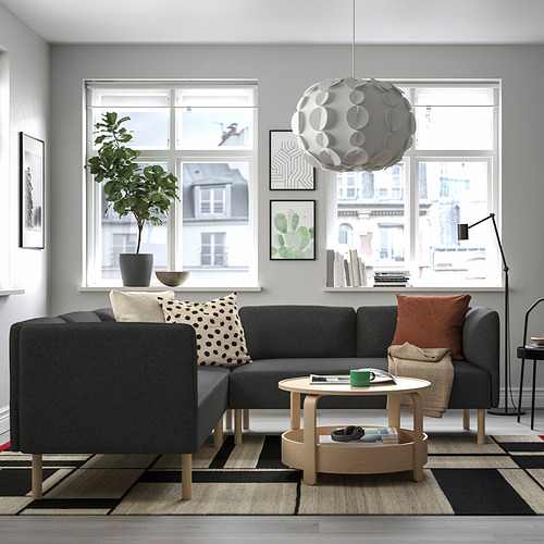 Sala de estar moderna con sofá LILLEHEM, alfombra, mesa de centro, planta, lámpara colgante, vista a la ciudad.