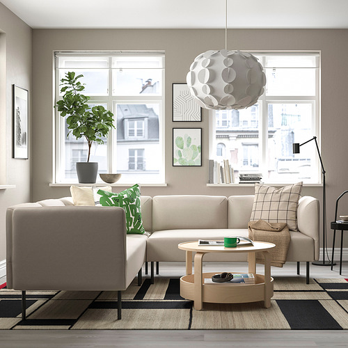 Salón contemporáneo con sofá LILLEHEM beige, cojines verdes, mesa de centro de madera, alfombra, lámpara de pie y planta en maceta junto a la ventana.