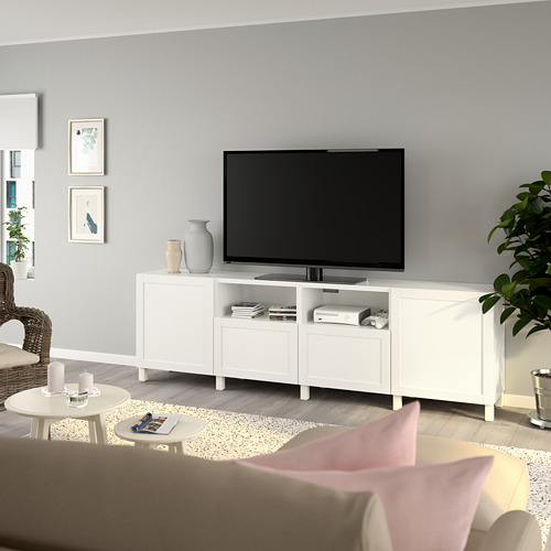 Sala de estar moderna con gran televisor en el banco BESTÅ, almacenamiento, jarrones, revistas, sillón, mesa de café, alfombra y arte.