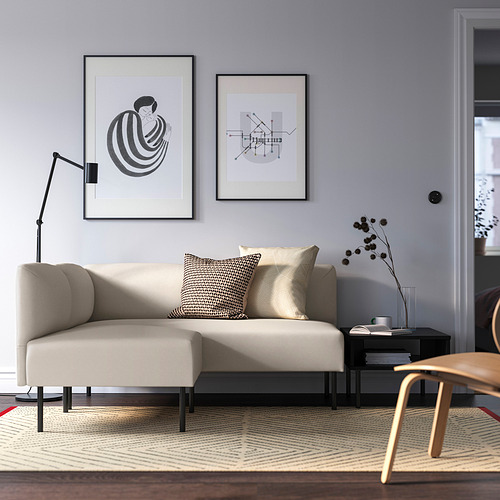 Sala de estar moderna con sofá LILLEHEM, arte abstracto, mesa oscura, alfombra geométrica, lámpara elegante, planta y silla, acogedora y contemporánea.