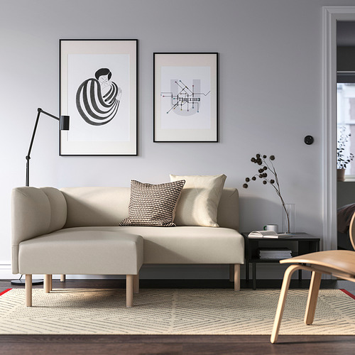 Sofá modular LILLEHEM en color beige claro, pieza central en salón minimalista con arte abstracto, alfombra beige/marrón, mesa auxiliar y lámpara alta.