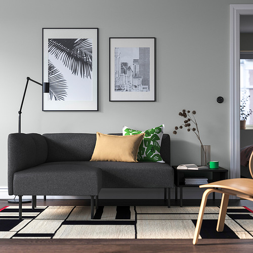 Sofá gris, arte, silla de madera, almohadas verdes, alfombra, lámpara de pie.