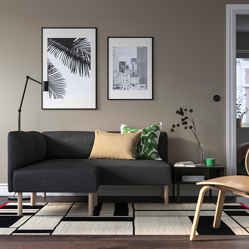 Sala de estar moderna con sofá LILLEHEM gris, cojines, arte, lámpara y alfombra estampada.