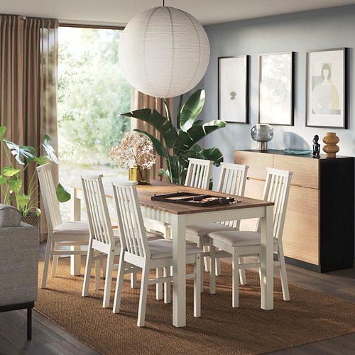 Comedor moderno con silla ÅLHULT colocada alrededor de una mesa de madera, asientos acolchados, lámpara colgante, aparador con decoración, alfombra, cortinas y plantas.