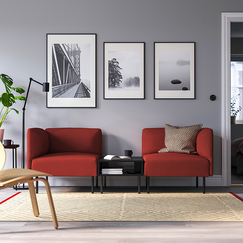 Sala de estar moderna: dos sofás modulares Lilleham rojos vibrantes, elegante mesa de centro, estampados elegantes y exuberante vegetación.