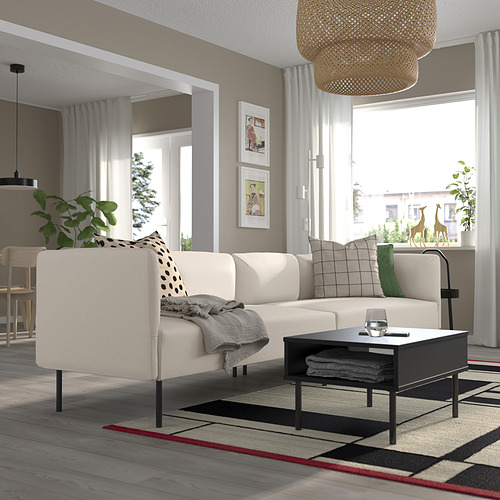 Salón moderno con sofá LILLEHEM, cojines, mesa de centro, mesa auxiliar con planta y alfombra grande.