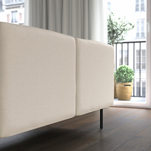 Sofá modular en habitación minimalista, de líneas limpias y tejido ligero, colocado cerca de una ventana.