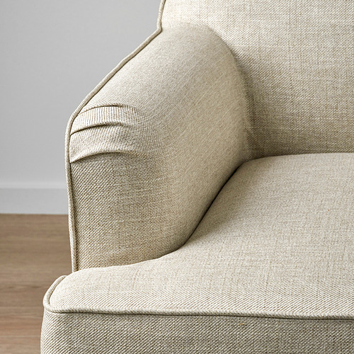 Moderno sillón de color claro con elegante tejido texturizado y sutil detalle de ribetes, asentado sobre suelo de madera.