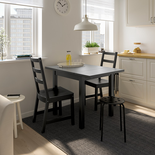 Pequeño juego de comedor NORDVIKEN negro en cocina luminosa. Incluye mesa y sillas extensibles, colocadas cerca de armarios blancos.