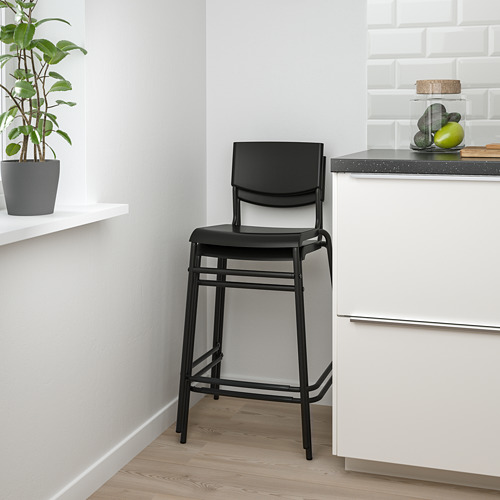 Moderno taburete de bar negro con asiento, reposapiés y diseño apilable. Fácil de limpiar para comidas informales.