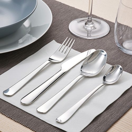 Mesa con tenedor, cuchillo y cucharas sobre servilleta, plato y vaso grises.