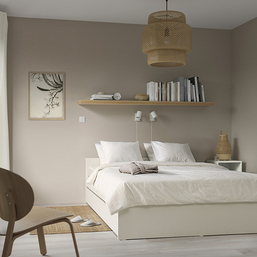 Dormitorio minimalista con somier VIHALS, nido, silla. Iluminación tenue, estantería, paredes grises, ropa de cama blanca.