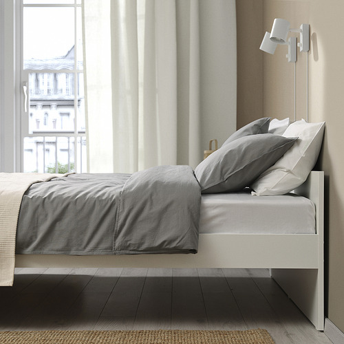 Estructura de cama moderna con ropa de cama gris, cerca de una ventana grande, incluye almacenamiento y tiene un diseño de listones para el flujo de aire.