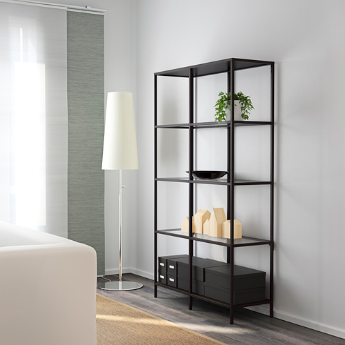 Estantería moderna con estantes de vidrio contra una pared, que sostienen objetos decorativos y una planta.