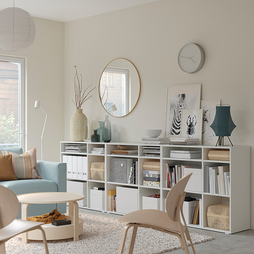 Sala de estar moderna con estantes de almacenamiento VIHALS blancos, sofá azul claro, silla de madera y elementos decorativos.