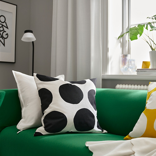 Sala de estar moderna con sofá verde, almohadas, plantas y obras de arte.