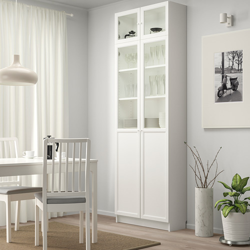 Librería BILLY blanca minimalista. Puertas altas, elegantes, de vidrio, llenas de placas.