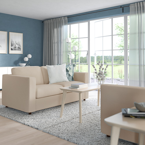 Sala de estar moderna con sofá VIMLE de color beige claro, de tamaño mediano en comparación con las ventanas, contra la pared azul.
