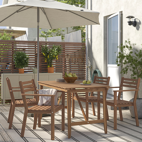 Juego de comedor al aire libre de madera de acacia con sillas acolchadas y sombrilla, perfecto para patios pequeños. Incluye cuenco de fruta, rodeado de plantas.