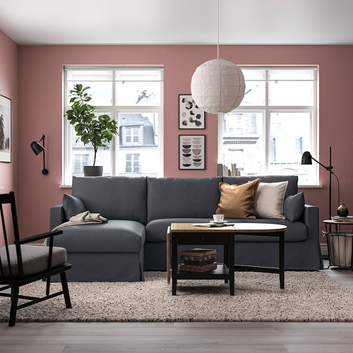 Sala de estar moderna con sofá seccional gris, cojines, lámpara y gran ventanal.