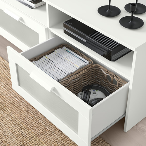 Mueble de TV blanco con cajón abierto que muestra cesta de mimbre, controlador de juegos y dvds.