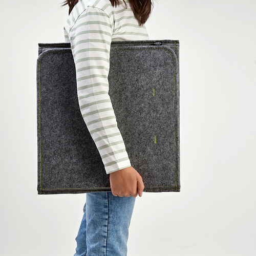 Persona sosteniendo separador de escritorio gris plegado, útil para crear privacidad y amortiguar el sonido.