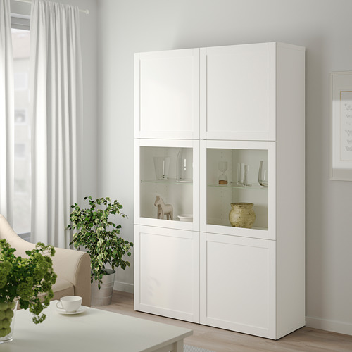 Armario BESTÅ con puertas de cristal, plantas y jarrones.