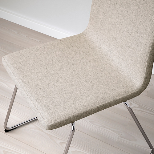 Silla moderna tapizada en color beige con base de patín cromado sobre suelo de madera.