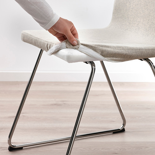 Persona ajustando el cojín de una silla LILLÅNÄS moderna, mostrando la funda extraíble y lavable para facilitar la limpieza.