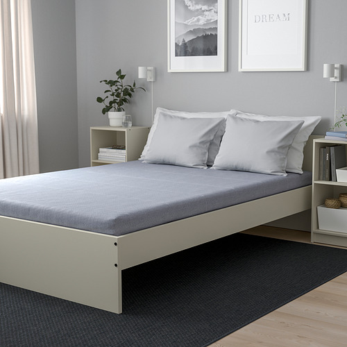 Colchón de espuma ÅGOTNES gris sobre cama de plataforma blanca, de 10 cm de altura, firme con capa superior suave.