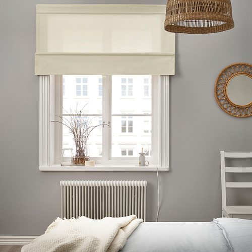 Dormitorio con gran ventanal gris y persiana romana beige. Lámpara colgante de cesta arriba y radiador blanco abajo. Jarrón decorativo en el alféizar de la ventana.