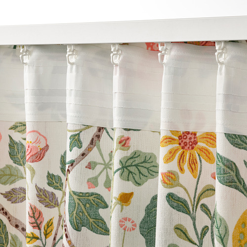 Un par de cortinas blancas, adornadas con coloridos patrones florales, colgaban cuidadosamente con lengüetas y ganchos visibles para filtrar la luz y la privacidad.