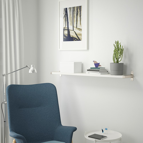 Silla azul, estantería con cactus, libros y cuadro.