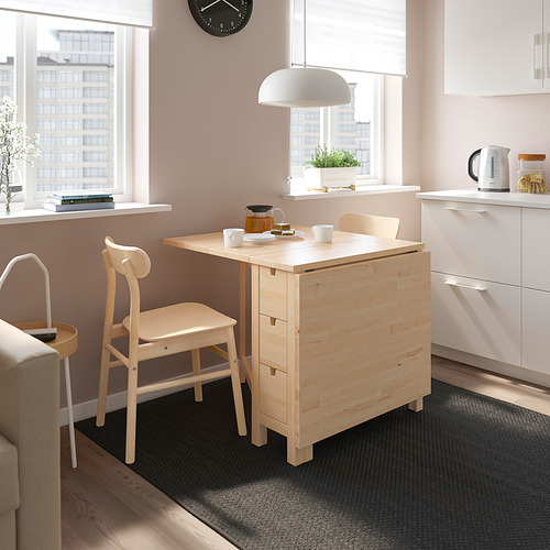 Pequeño juego de comedor NORDEN de madera clara con mesa, dos sillas y alfombra en un acogedor espacio de cocina.