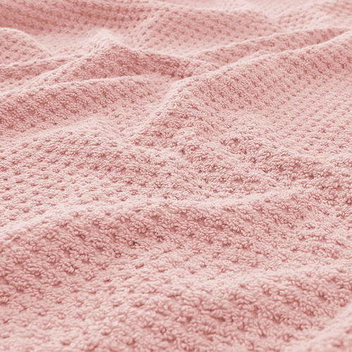 Toalla suave y texturizada de color rosa claro en primer plano, que muestra su calidad afelpada y absorbente.