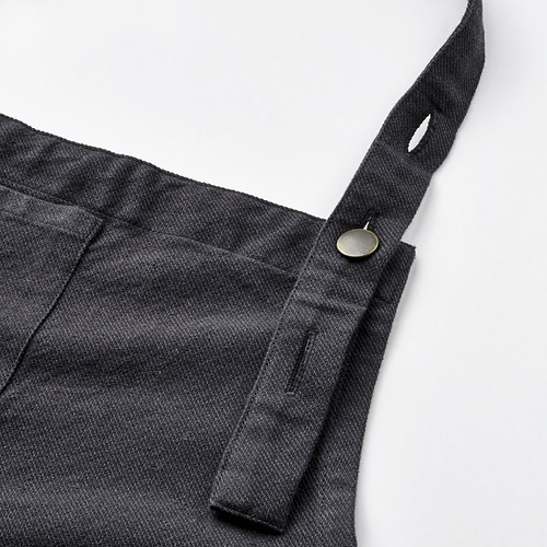 Delantal con cuello ajustable, botón metálico resistente y detalle de bolsillo en tela.