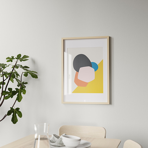 Un moderno marco de madera cuelga de una pared, mostrando colorido arte abstracto. Debajo de ella, una mesa de comedor sostiene vasos, tazas y una planta.