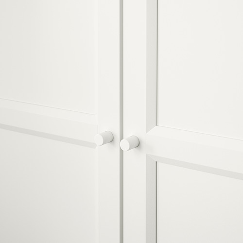 Mueble blanco minimalista con pomos redondeados, puertas cerradas y juntas sin costuras.