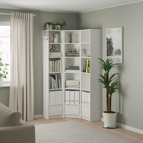 Estantería blanca BILLY con libros y plantas entre el sofá y la ventana.