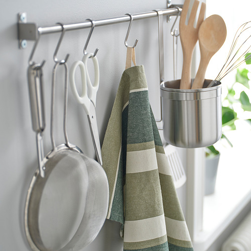 Rejilla de cocina con ollas, tijeras, paño de cocina a rayas y utensilios en un recipiente de metal.
