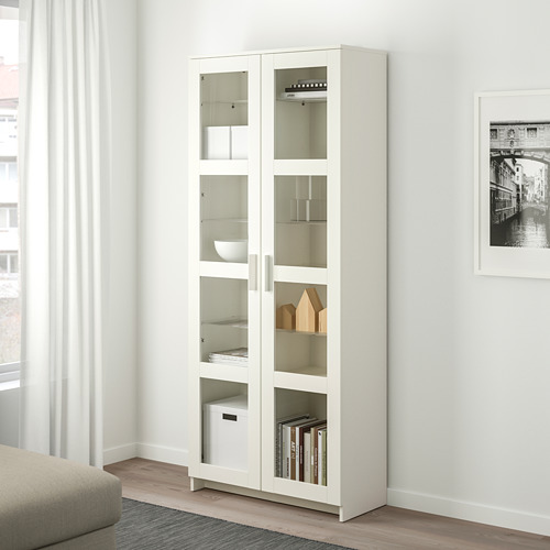 Mueble con puerta de cristal BRIMNES blanco. El diseño alto, delgado y moderno se adapta a los libros, la decoración. El estante muestra los artículos claramente mientras los protege.