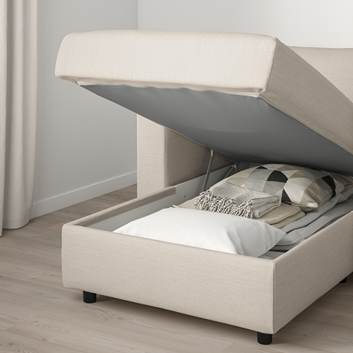 Un sofá VIMLE de color crema con almacenaje. La chaise longue tiene una tapa abierta que deja ver las almohadas en su interior.