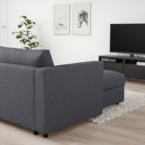 Sala de estar minimalista con sofá VIMLE, suelo de madera oscura, alfombra blanca, tv y arte de pared.