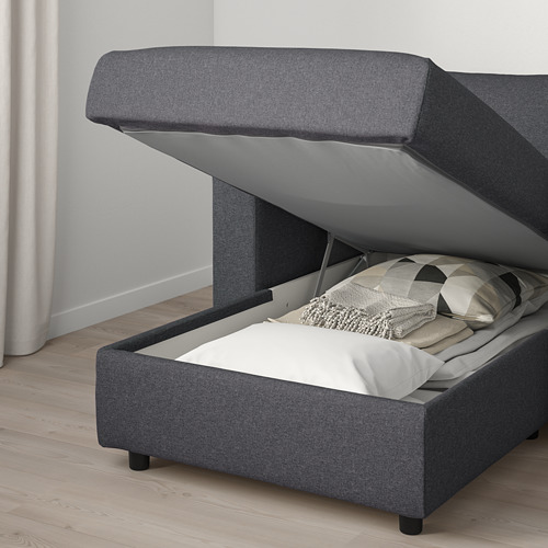 Moderno sofá cama tapizado en gris con almacenaje, abierto para revelar cojines.