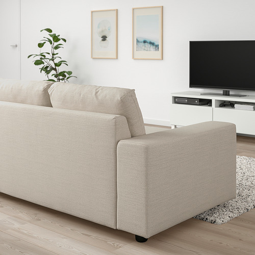 Sofá VIMLE beige sobre suelo de madera con tv, planta y arte.